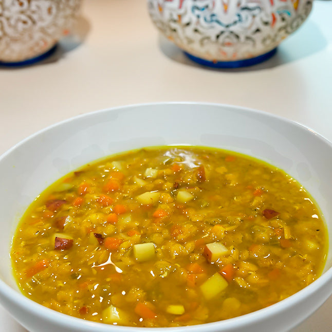 A bowl with Yemeni red lentil soup with "Souper spice" spice blend. Next to it other middle-eastern table ornaments.