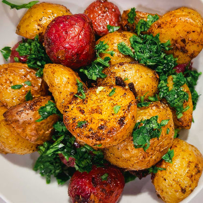 Bowl with beautiful roasted potatoes made with Mediterranean spice blend "Potayto-Potahto". Garnished with chopped parsley.
